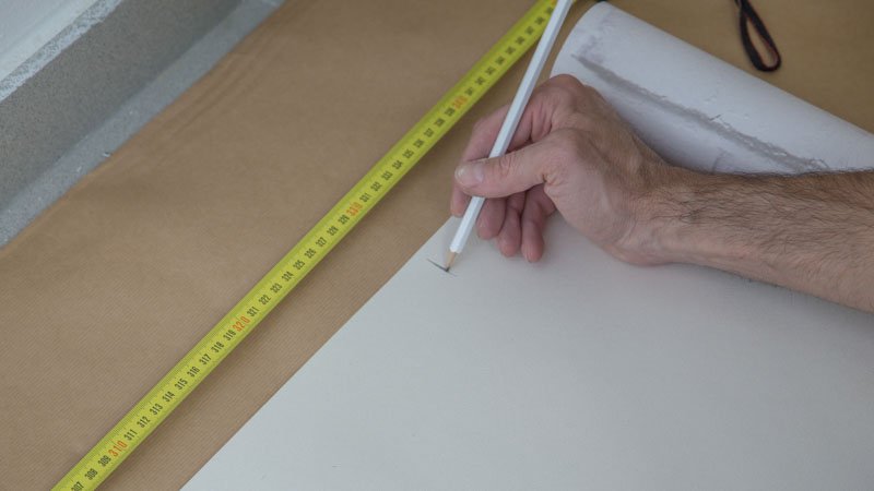 Lápiz marcando las medidas sobre el papel pintado