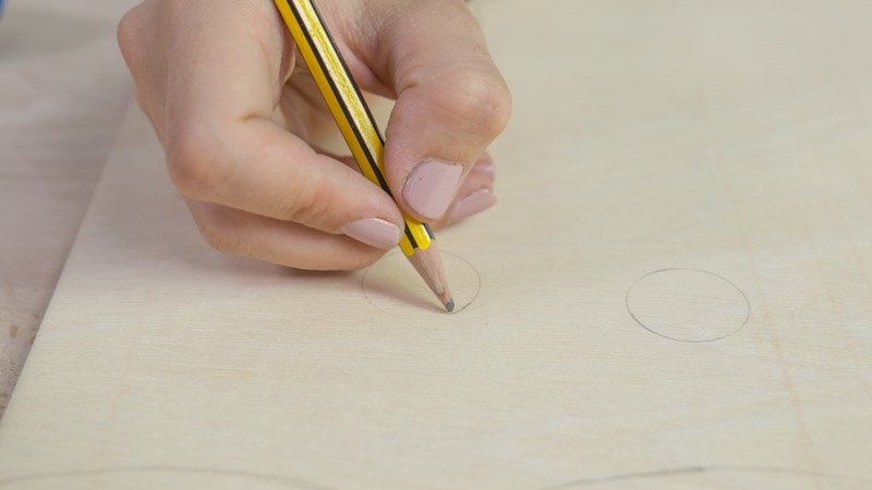 Lápiz dibujando las piezas en la madera