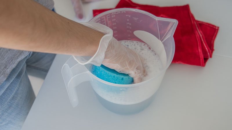 Esponja limpiando la nevera con agua y jabón