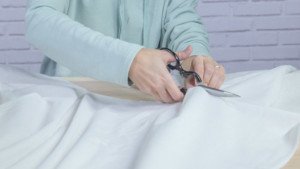 Tijeras cortando la tela que servirá de cesto para la ropa