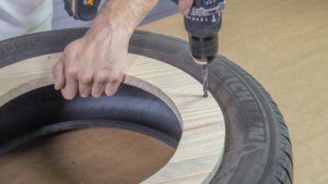 Taladro haciendo los agujeros en la madera para poder unirla al neumático