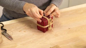 Pasar el hilo para colgar el adorno por la cuerda que cierra la caja de regalo.