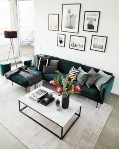 Salón con paredes blancas y colores en blanco y negro con sofá en color verde para romper.