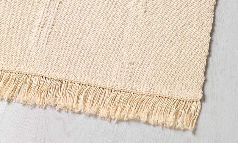 Detalle de alfombra de tejido de algodón de  color crudo