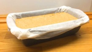 Masa cruda del pan de plátano en molde rectangular con papel de horno