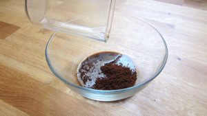 Azúcar blanco, café soluble y agua en un cuenco transparente sobre una encimera de madera