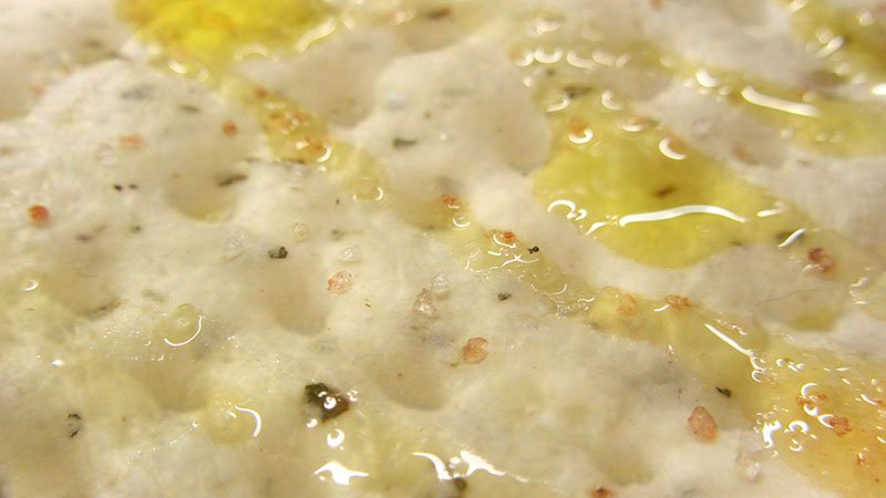Detalle de la masa de focaccia cruda con aceite y sal