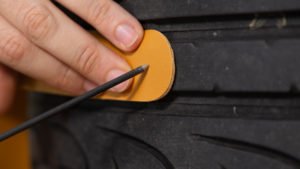 Punzón abriendo un agujero en una tira de cuero para fijarla al neumático